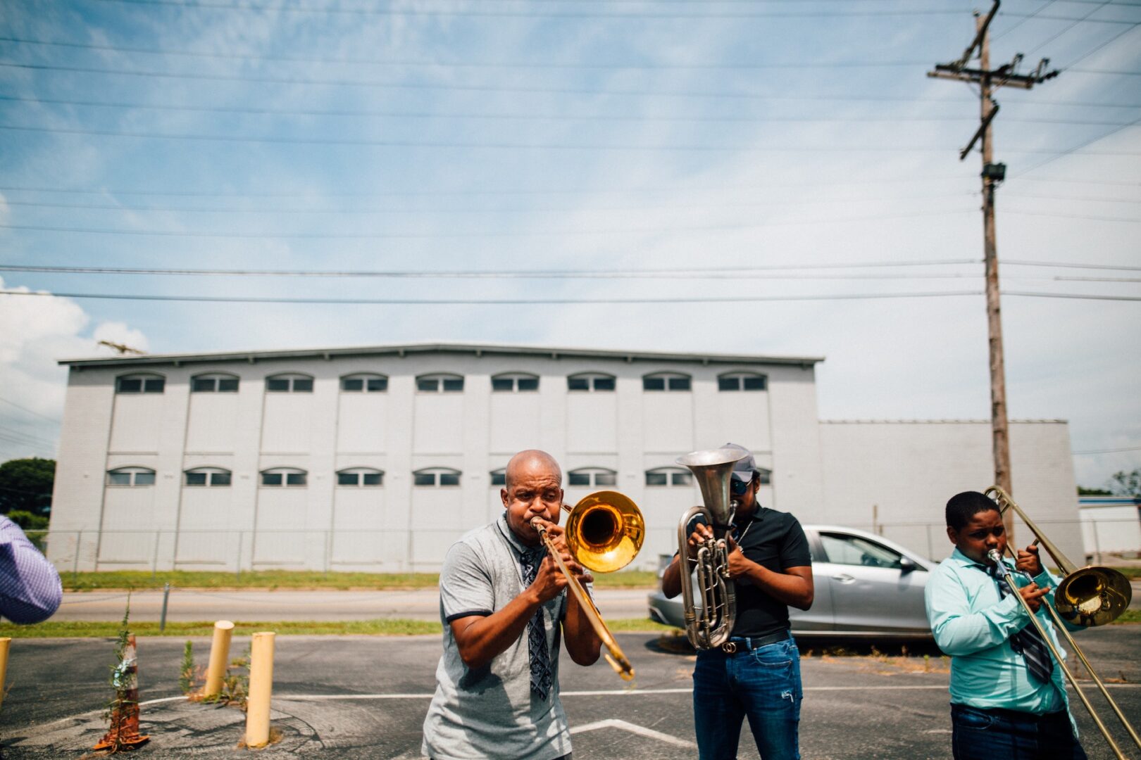 Two men playing their instruments in a parking lot.